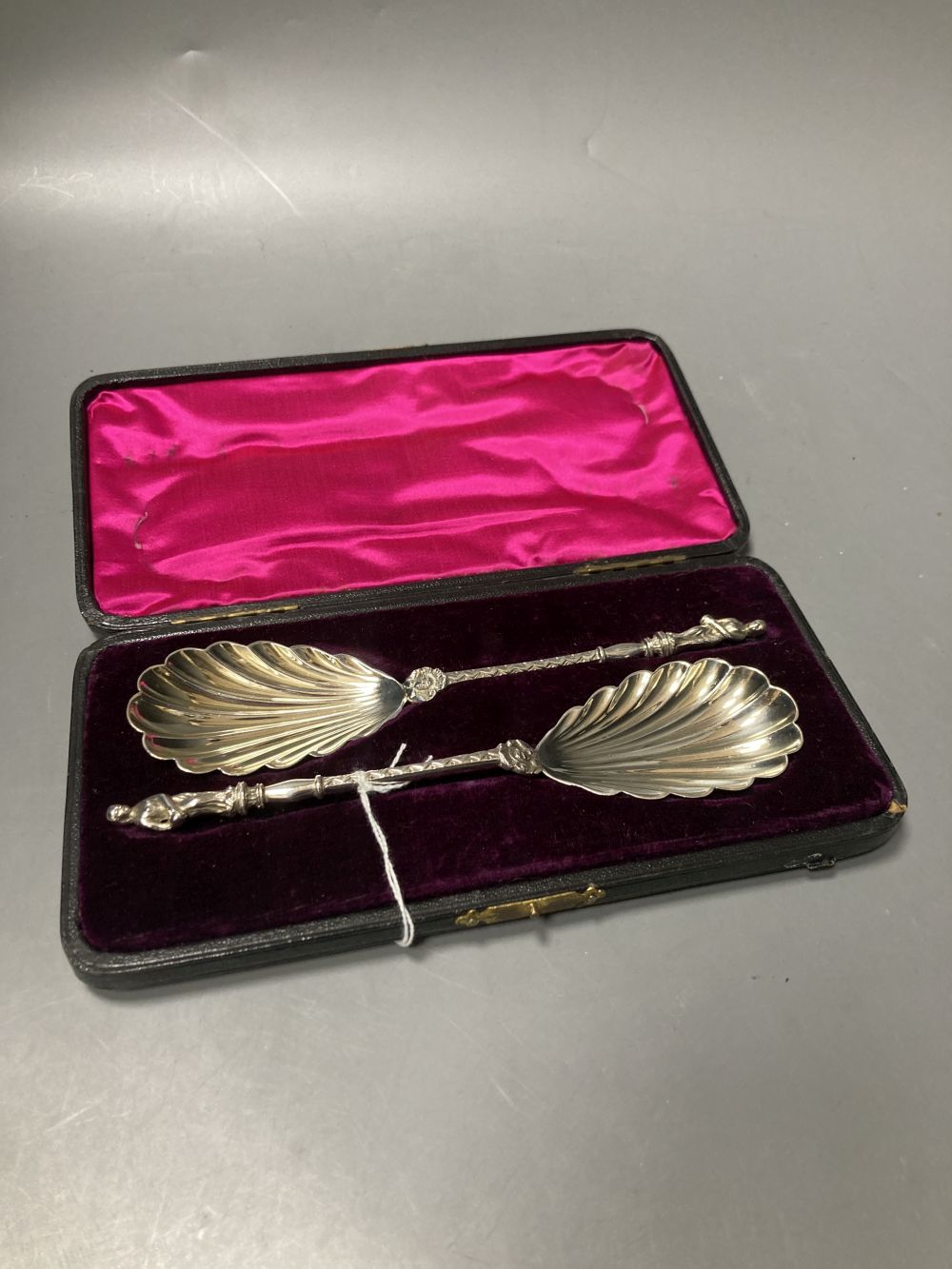 A cased pair of late Victorian silver serving spoons, with shell bowls and figural terminals,
